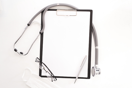 Top view flatlay of doctors tools on white desk composition of blank  clipboard, glasses and stethoscope, copy space