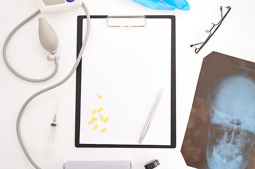 Top view flatlay of doctors tools on white desk composition of blank  clipboard, glasses and x-ray image, copy space