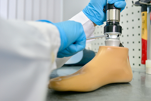 Close up shot of unrecognizable prosthetist assembling prosthetic leg in modern  laboratory