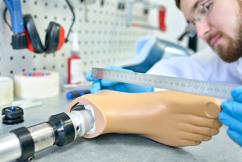 Close up of unrecognizable prosthetist measuring artificial foot while working in design laboratory