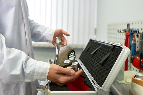 Close up of unrecognizable  prosthetist putting brand new leg prosthesis in protective case  while working at modern laboratory