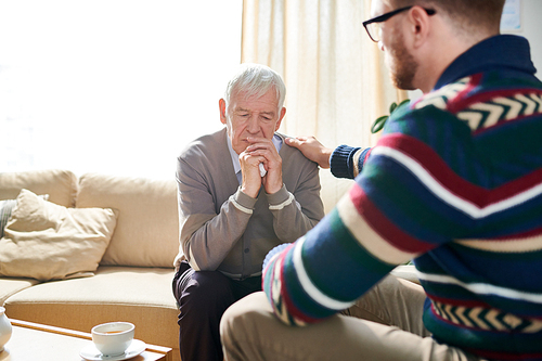 Back view portrait of male psychologist consoling depressed senior man during therapy session, copy space