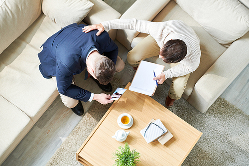 Above view portrait of psychiatrist consulting grieving young man holding photo of wife, copy space