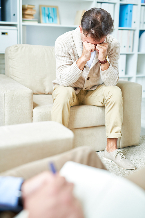 Portrait of crying man sharing mental problems with unrecognizable psychologist during therapy session, copy space