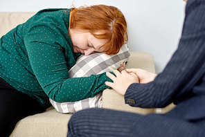 Close-up shot of friendly psychologist reassuring crying patient suffering from eating disorder while having appointment at cozy office