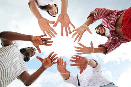 Low angle view of cheerful young people making a circle from their hands outdoors