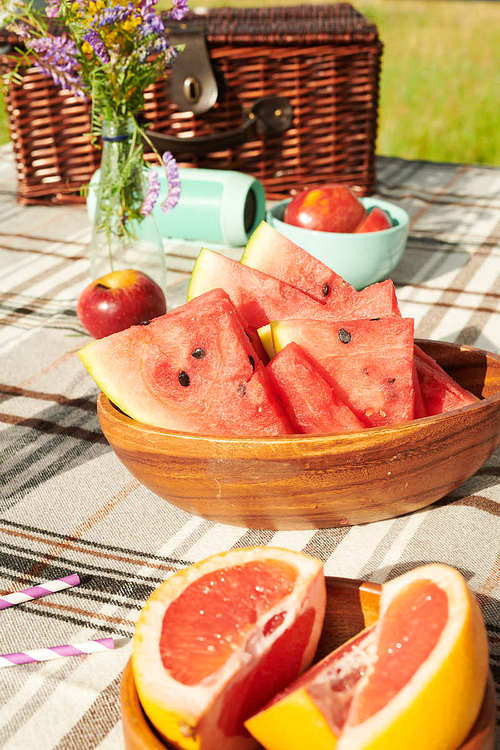 Close-up of table with slices of watermelon in basket and ripe grapefruit on it