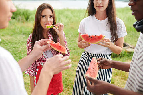 Young people standing and enjoying watermelon on the nature