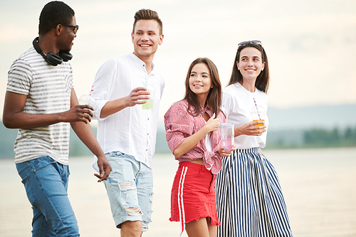 Group of happy teenagers drinking cocktails having fun outdoors