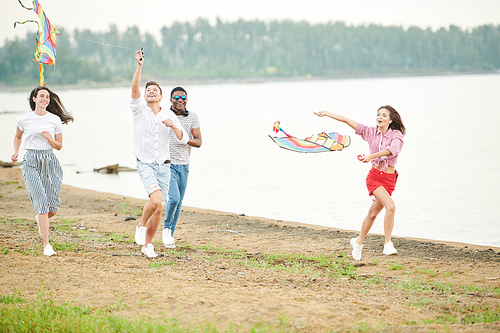 Young people having fun outdoors, playing with kites together