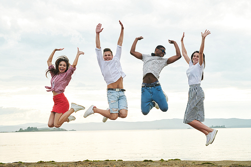 Happy young people jumping together on the beach