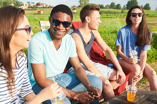 Group of cheerful young friends having fun at picnic outdoors