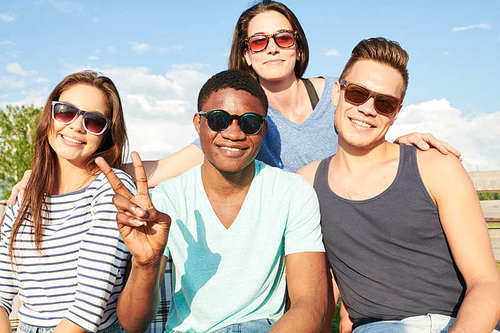 Portrait of young people wearing sunglasses sitting together and smiling