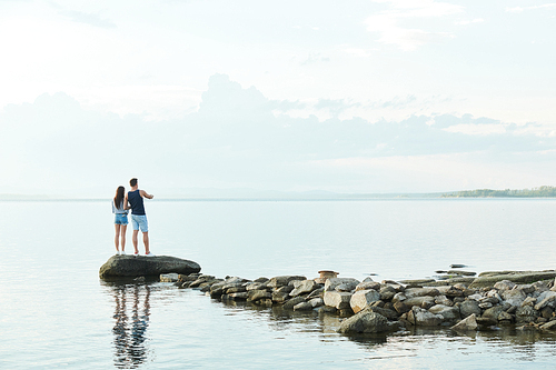 Rear view of young couple standing on stones and enjoying beautiful view