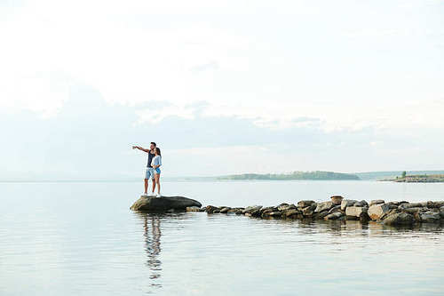 Young couple standing on the pier and looking at beautiful landscape