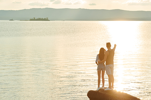 Rear view of young man showing a beautiful view of the lake to his girlfriend