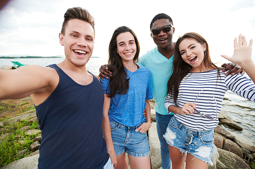 Portrait of cheerful young friends making a selfie portrait against the lake