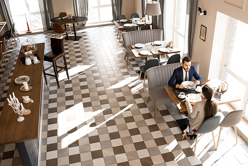 Directly above view of confident handsome businessman sharing his idea with business colleague while they resting in restaurant and eating meal