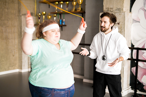 Waist up portrait of personal coach training  fat woman in fitness club, copy space