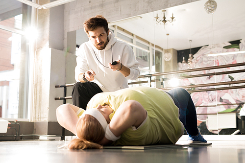 Portrait of obese young woman doing crunches during workout with fitness instructor in sunlight, copy space