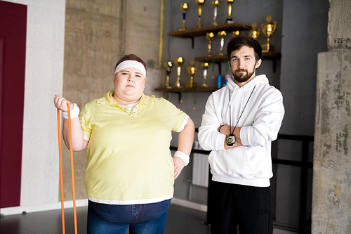 Waist up portrait of confident overweight woman posing with personal fitness coach during workout