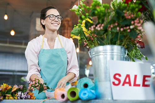 Portrait of smiling young woman arranging bouquets while working in flower shop