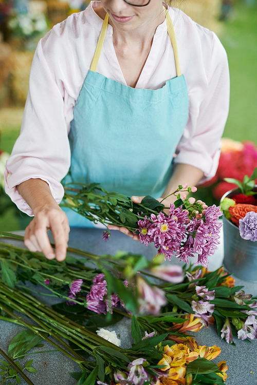 Mid section portrait of female florist arranging bouquets while working in flower shop