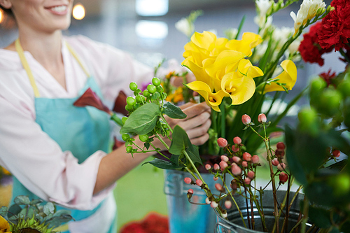Closeup of unrecognizable female florist arranging beautiful yellow flowees at counter in small flower shop, copy space