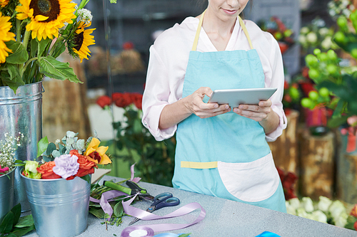 Mid section portrait of unrecognizable florist using digital tablet in shop