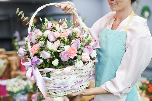 Mid section portrait of unrecognizable female florist holding flower basket with beautiful pastel colored roses while working in flower shop