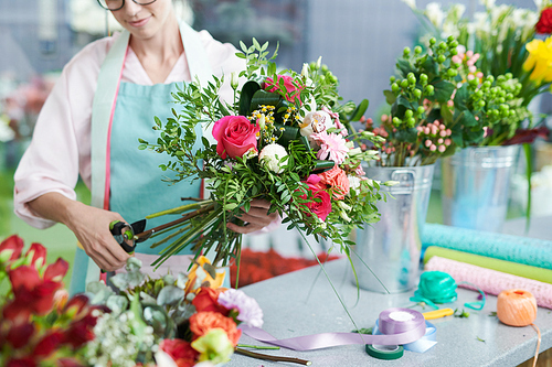 Crop view of smiling woman arranging flower bouquet in shop