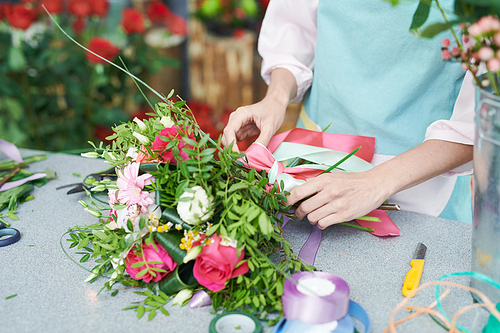 Closeup of unrecognizable florist tying beautiful rose boquet