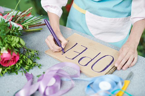 Close up of unrecognizable female shopkeeper making OPEN sign on paper in small flower shop, copy space
