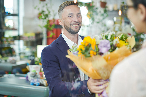 Waist up portrait of smiling handsome gentleman buying beautiful bouquet in flower shop for date, copy space