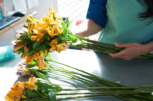 Closeup shot of unrecognizable female florist arranging yellow alstromeria flowers while making bouquets in flower shop