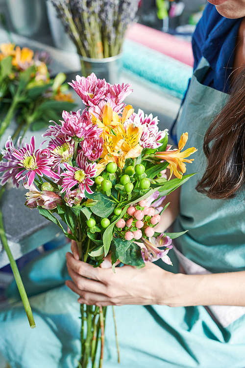Portrait of unrecognizable female florist holding beautiful bouquet lit by sunlight while working in flower shop