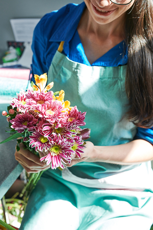 Closeup portrait of female florist arranging  flowers while making bouquets in flower shop
