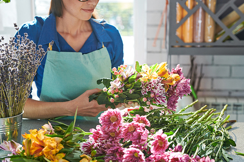 Close up portrait of female florist arranging  flowers while making bouquets in flower shop