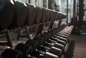 Background image of straight rows of dumbbells on equipment stand in modern gym, copy space