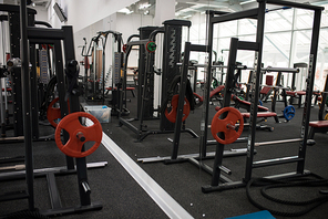 Background image weight training stands with barbells and  benches in empty modern gym, copy space