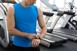 Mid section portrait of unrecognizable muscular man checking fitness tracker after working out in gym, copy space