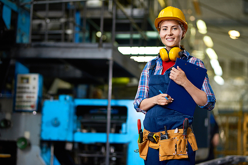 Portrait of smiling woman wearing  hardhat  working in modern plant