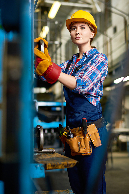 Portrait of female factory worker setting up machine units looking away  in modern plant