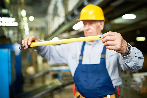 Portrait of senior man unrolling reel tape while working in modern factory workshop