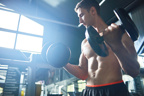 Motivational low angle portrait of sexy muscular man with bare chest working out in modern gym, copy space