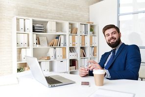 Portrait of successful  bearded businessman smiling happily while working  in modern office