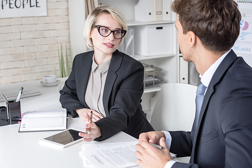 Portrait of two successful business partners discussing deal during meeting in office, focus on young blonde businesswoman