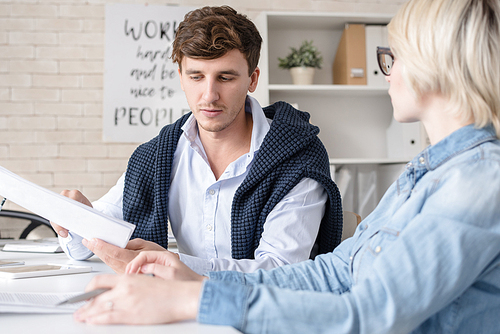 Portrait of two modern business people man and woman discussing work sitting at table during meeting in office