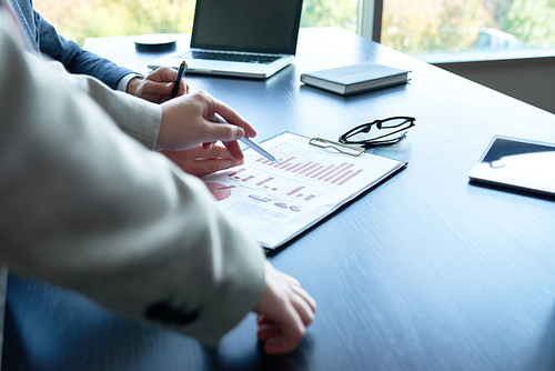 Close up of unrecognizable business people  pointing to statistics graph on desk analyzing marketing data in modern office, copy space