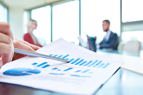 Closeup of unrecognizable business person  pointing to statistics graph analyzing marketing data  with other people in background, copy space